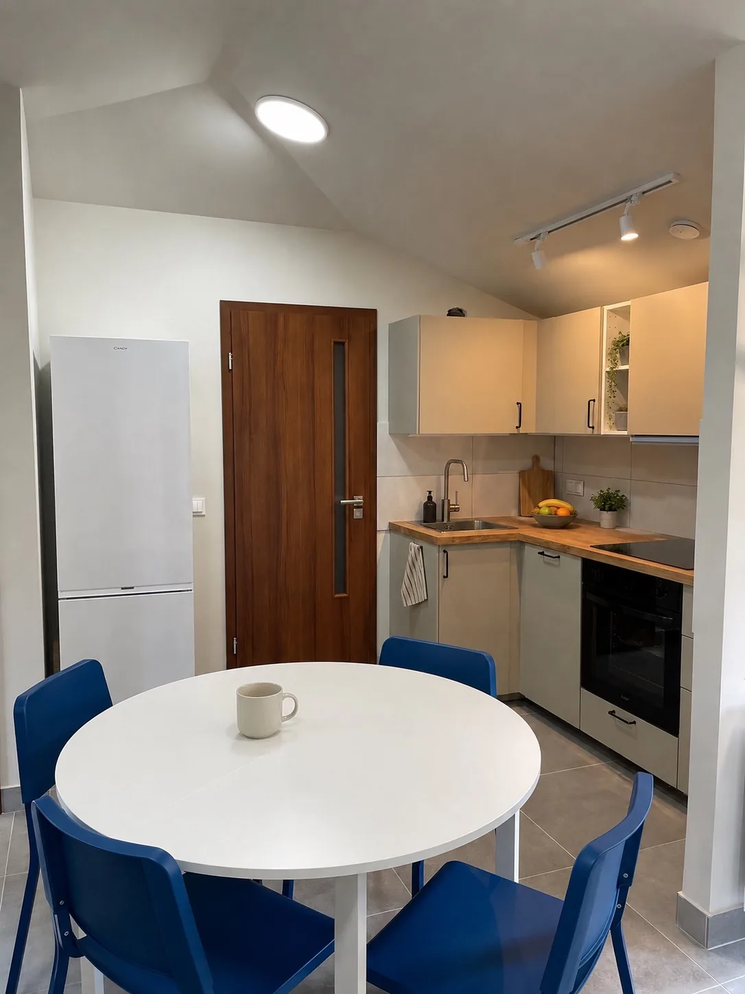 Campus Loft — kuchnia z okrągłym stołem i niebieskimi krzesłami